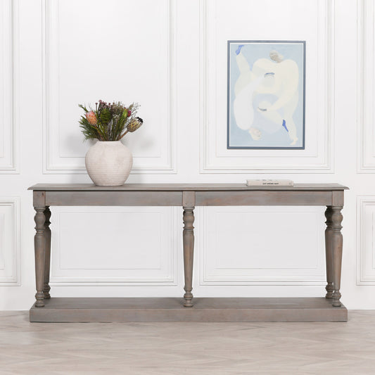 Wooden console table with decorative items against a white paneled wall.
